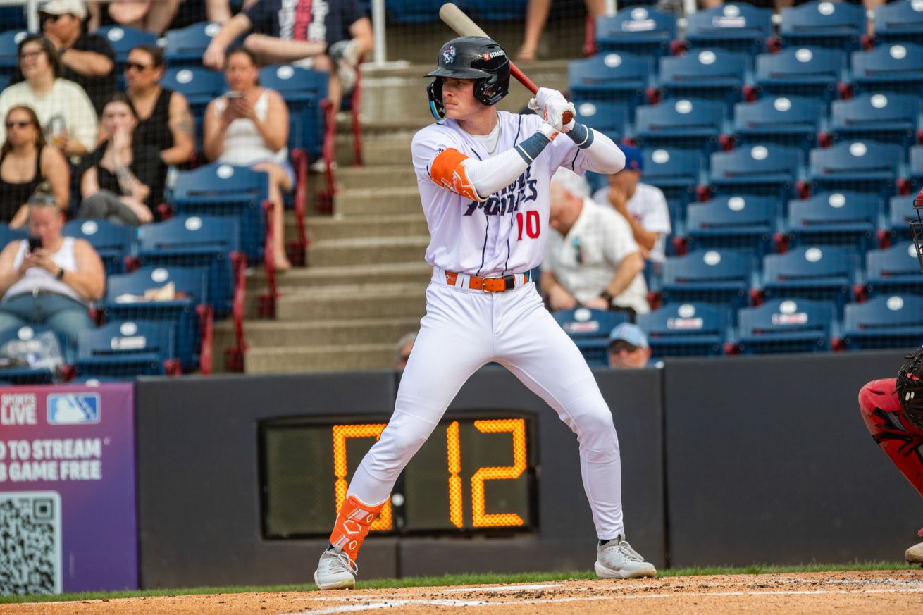 Carson Benge stands in the batter’s box in a white Rumble Ponies uniform with blue lettering and a blue helmet