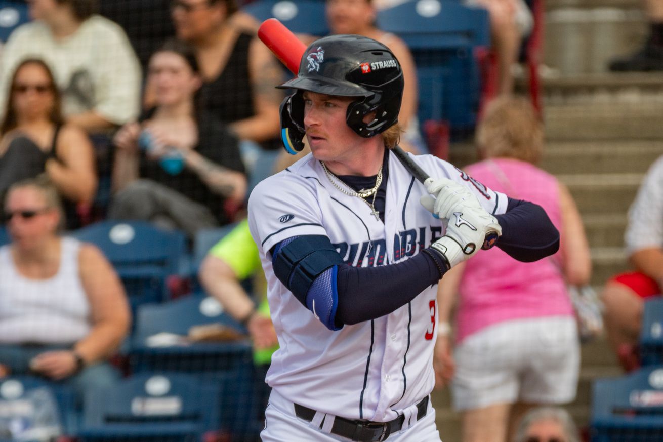 Ryan Clifford standing in the batter’s box in a white Rumble Ponies uniform with a blue helmet and blue sleeves