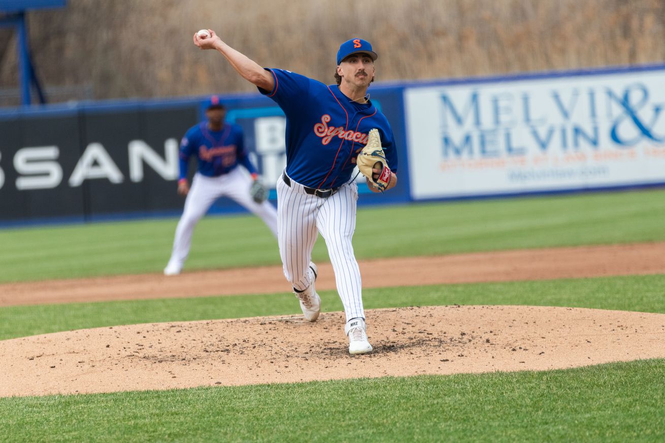 Brandon Sproat throws a pitch in a blue Syracuse Mets uniform with orange and grey script and white pants.