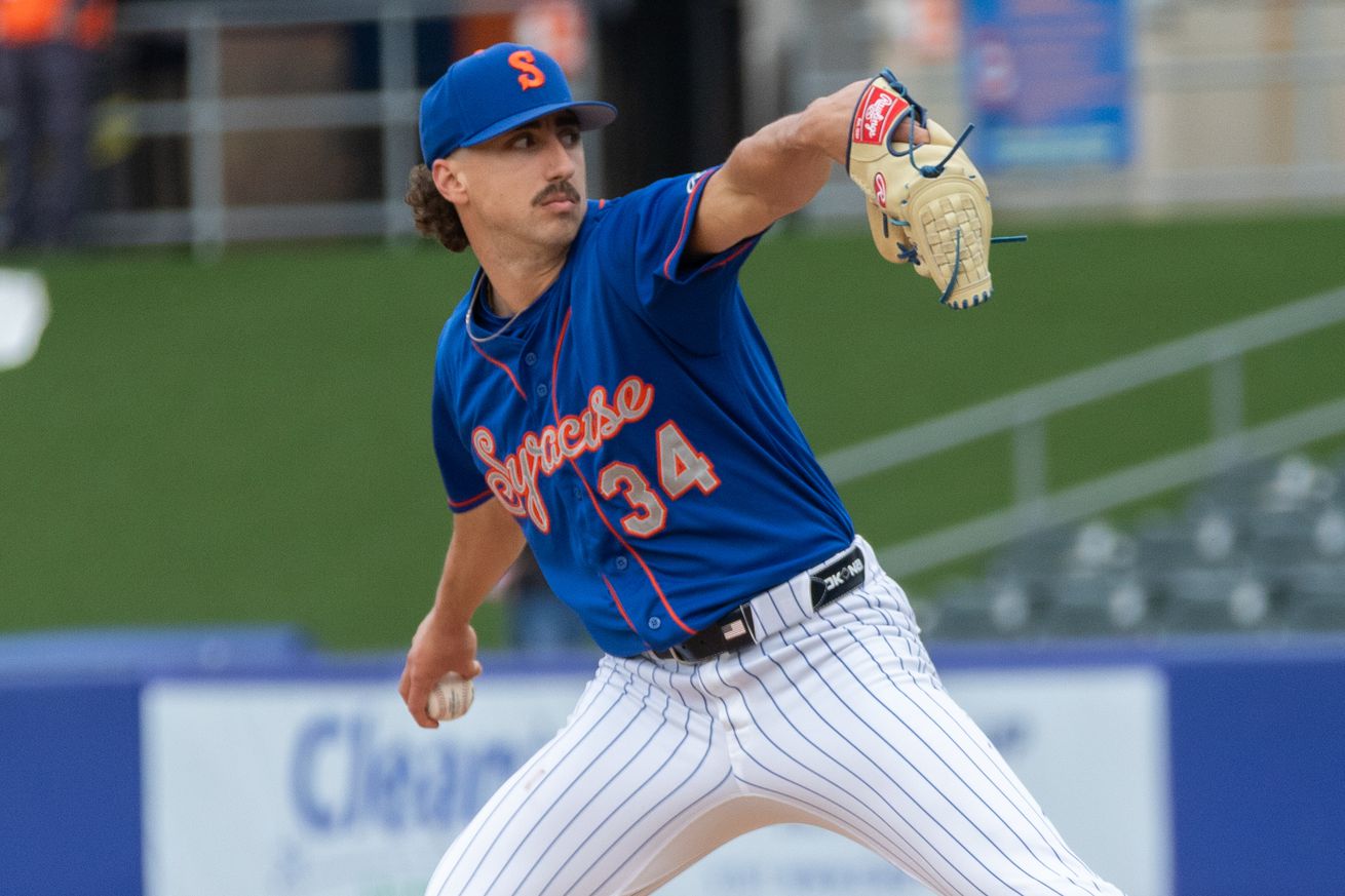 Brandon Sproat throws a pitch in a blue Syracuse Mets uniform with orange and grey script and white pants.
